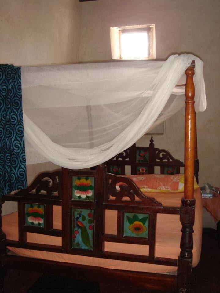 The traditional bed in the inner bedroom, with fan and mosquito net.