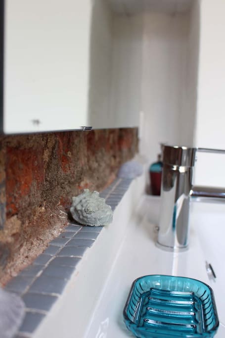 Moderno baño con gresite y pared de ladrillo visto.