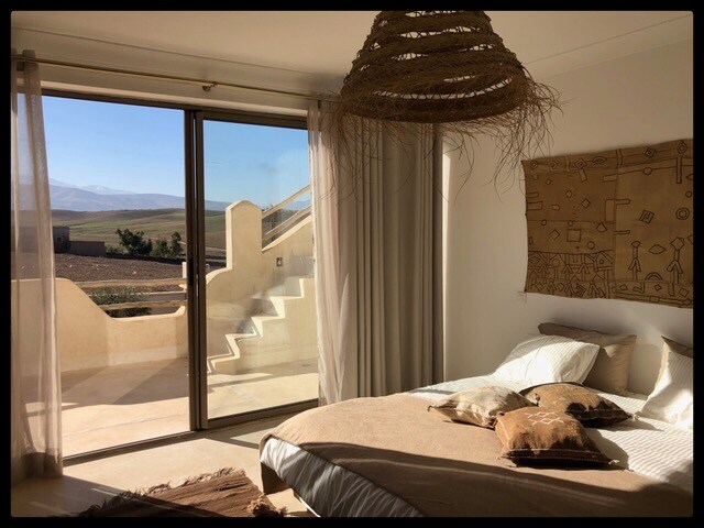 ห้องนอนขนาดใหญ่ที่ชั้น 1 ตกแต่งอย่างครบครันด้วยโทนสีธรรมชาติและเพลิดเพลินกับระเบียงพร้อมวิวแอตลาส