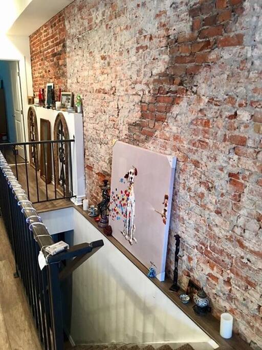 Exposed brick covers the length of the north wall of our home. The stairs lead to our living room/mancave. Guest are more than welcome to hangout here.