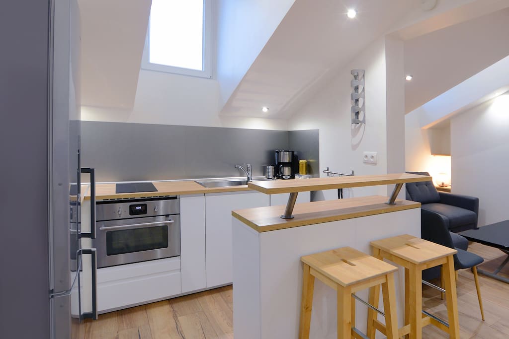 Cuisine ouverte très fonctionnelle avec de nombreux rangements : plaque à induction, four/four micro-ondes, cafetière, grille pain, bouilloire