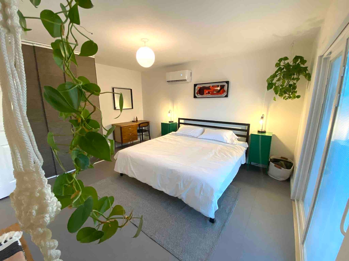 חדר שינה אחד, מזרן קינג סייז על מסגרת המיטה בפלטפורמה, אזור משרד עם שולחן כתיבה, ארון, דלתות הזזה מזכוכית ליציאה לחצר האחורית 