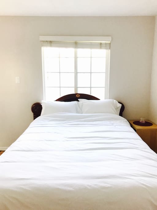 Queen size bed with clean white sheets and cover.