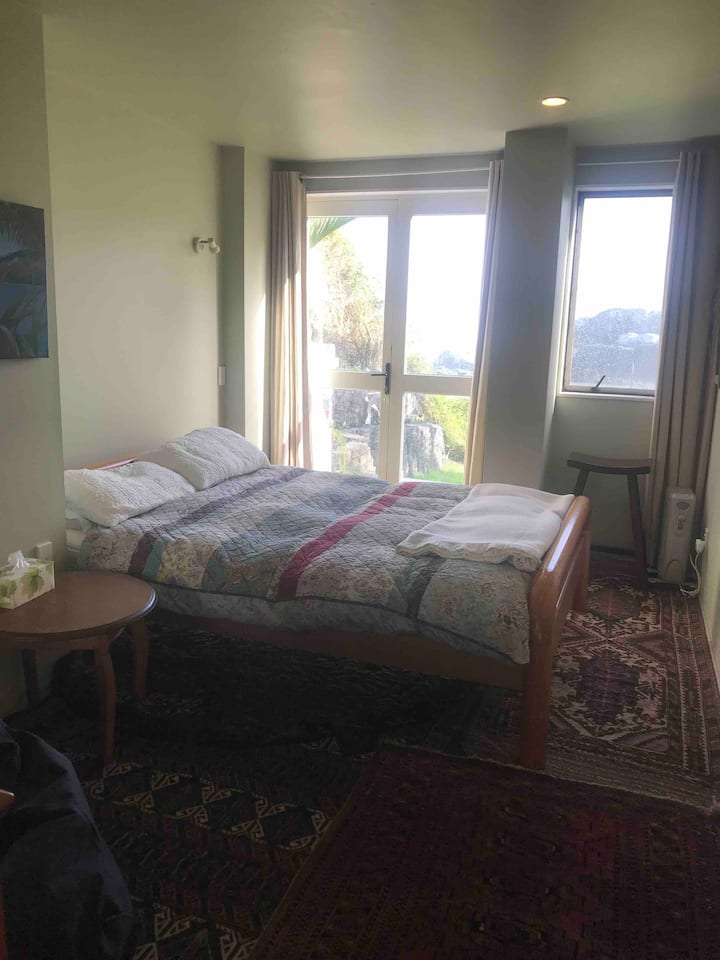 Kitanda cha malkia chenye milango iliyo wazi kuelekea mwonekano wa bahari.