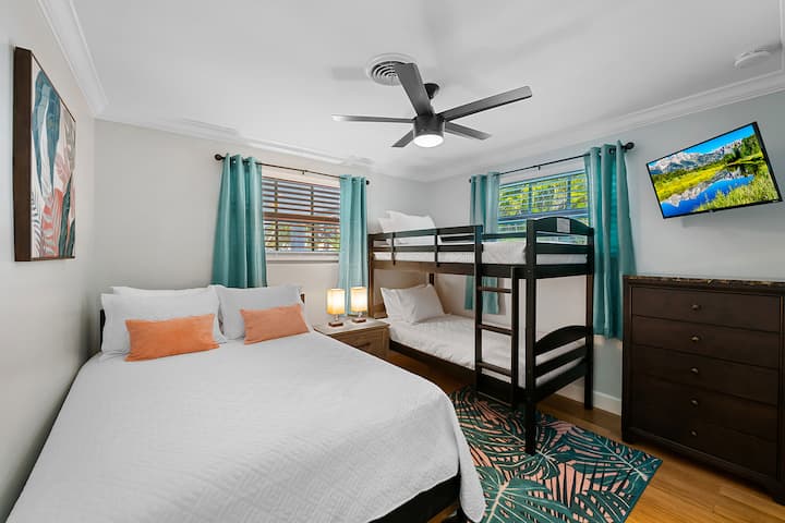 guest bedroom with comfy queen sized bed and bunkbed, smart tv, and usb charging lamps