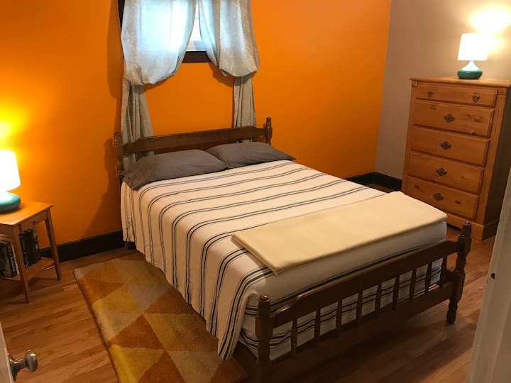 El dormitorio naranja más pequeño hacia la parte trasera de la casa tiene una cama de tamaño completo.