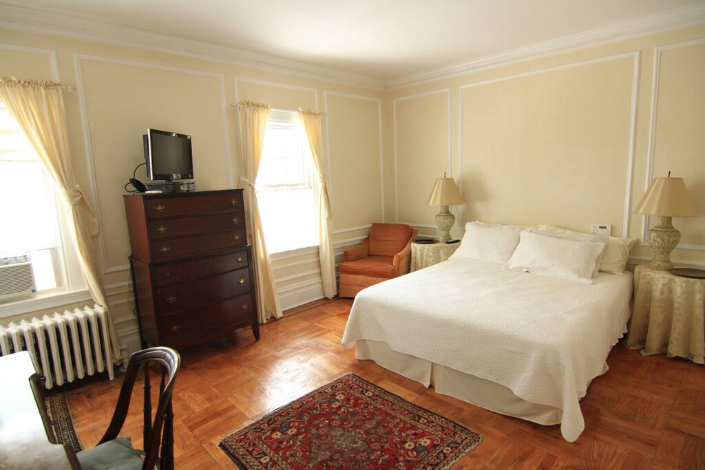 A spacious, sunny double room with a queen bed, desk, TV and en suite bathroom