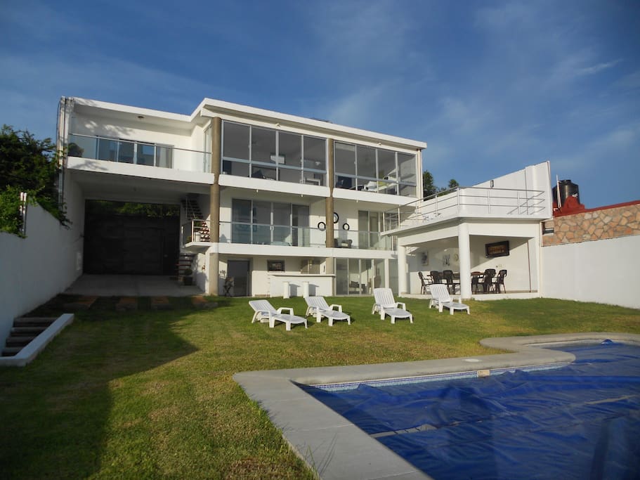 Vista general de la casa. Se aprecia la casa en 3 niveles , asoleadero , comedor exterior , estacionamiento para 4 autos, jardín y alberca.