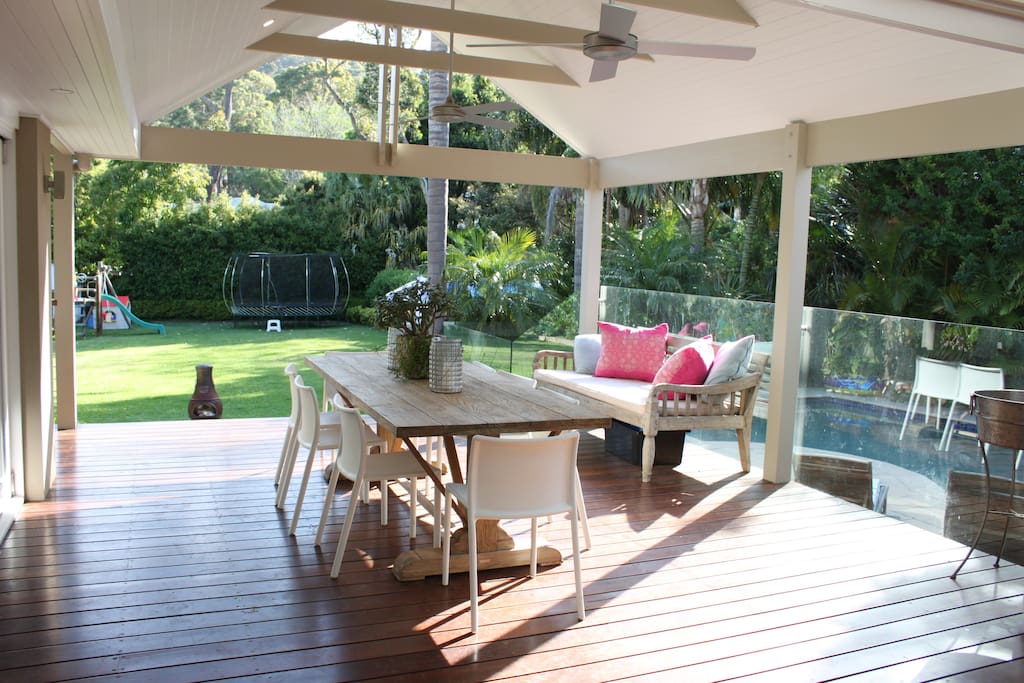 View from kitchen through bi-fold doors to outdoor room, pool and expansive backyard