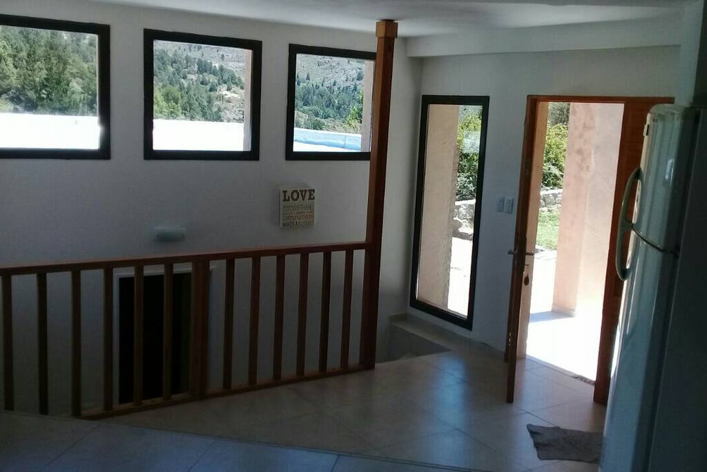 Puerta de ingreso a la casa: a la derecha las escaleras que bajan a los dormitorios. A la izquierda el living con cocina, baño y deck con asador