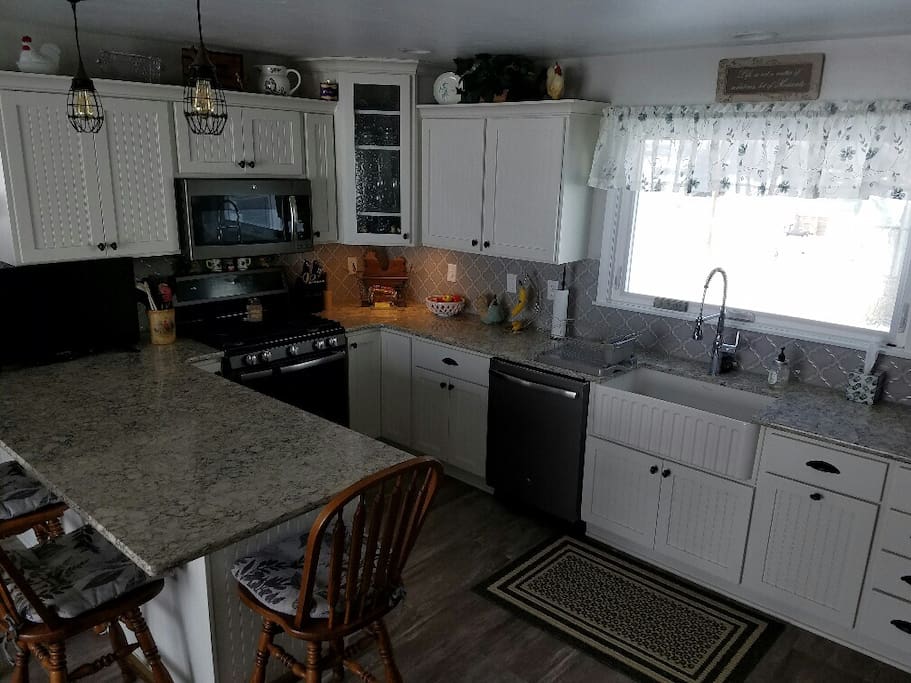 Kitchen with stove, dishwasher, microwave, farm sink, tv.