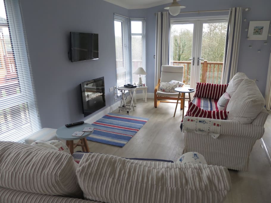 Nautical themed lounge with two relaxing sofas . Television with Freeview and electric fire Two radiators . Double patio doors.