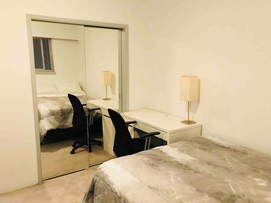 Spacious bedroom with a closet-mirror, computer table with chair, and a sofa bed.