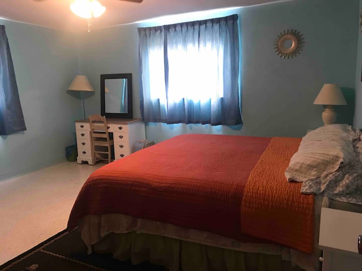 غرفة النوم الرئيسية وسرير بحجم كبير وخزانة ملابس وخزانة ملابس ومكتب وطاولات جانبية.