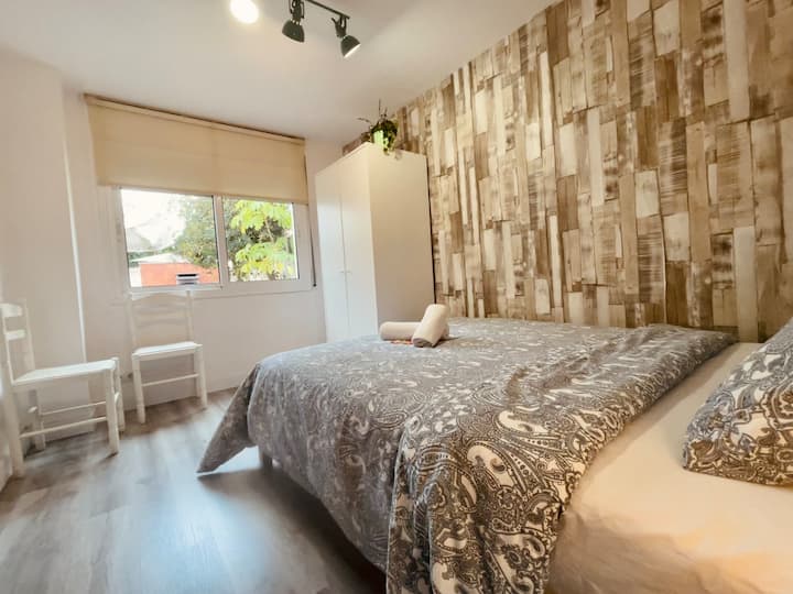 Habitación privada con cama doble y vistas al jardín y la piscina. Equipada con colchón de gama superior, armarios y perchas, albornoz, toallas, champú, etc. y incluso cargador de smartphone!