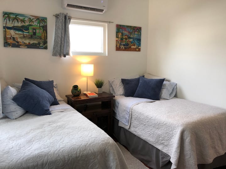 Dhomë gjumi me dy krevate dopio, njësi e veçantë AC, ventilator tavani, dollap dhe TV.