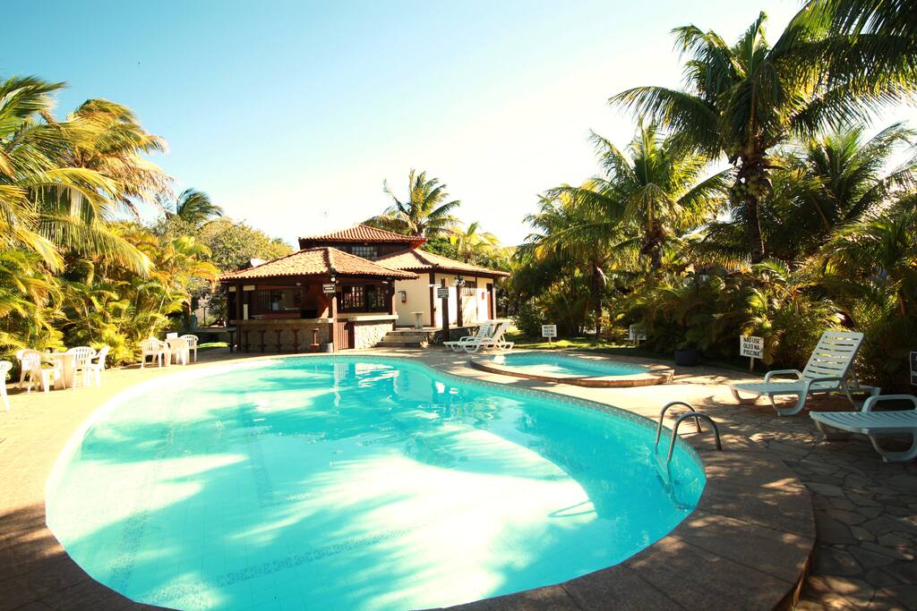 Piscina do condomínio e churrasqueira ao fundo