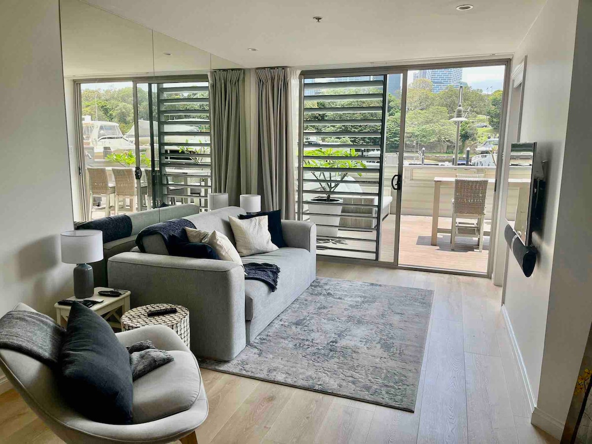 Woonkamer met uitzicht op het water, de haven, de skyline van de stad, Domeinpark en luxe jachten.