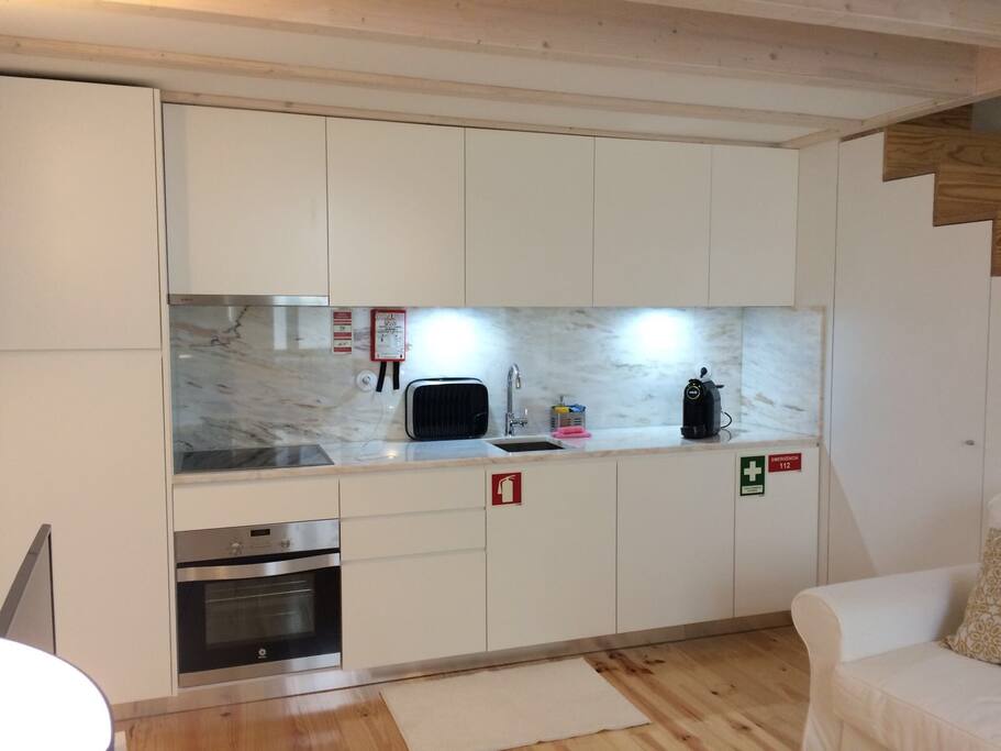 Kitchenette equipada com loiça, frigorífico, fogão, forno, máquina de lavar e máquina de café