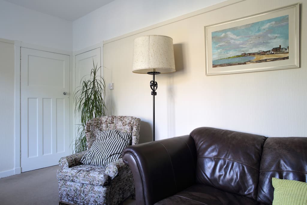 Living room with couch, 50" HDTV, dining room table with 4 chairs and arm chair. Views to rear patio garden.