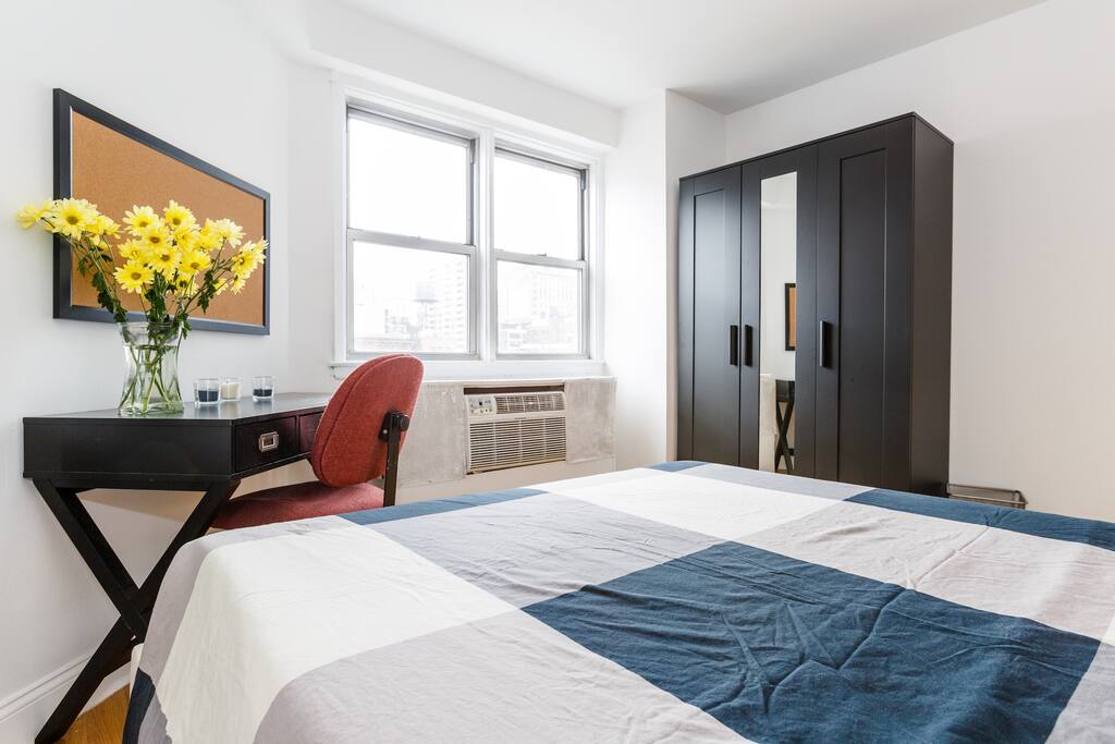 Spacious bedroom with full bed, desk, chair, and wardrobe cabinet