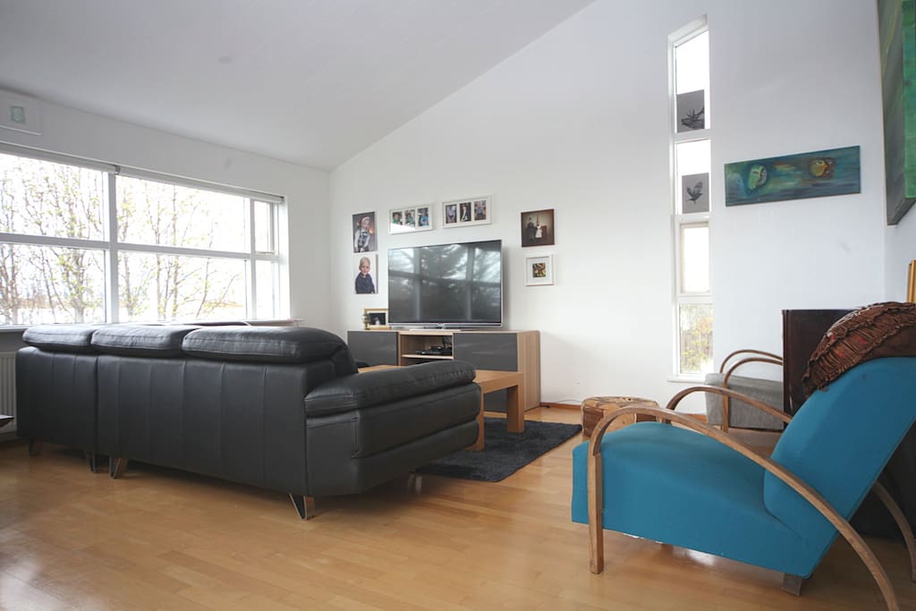 Spacious livingroom with a large TV and many sofas and seating