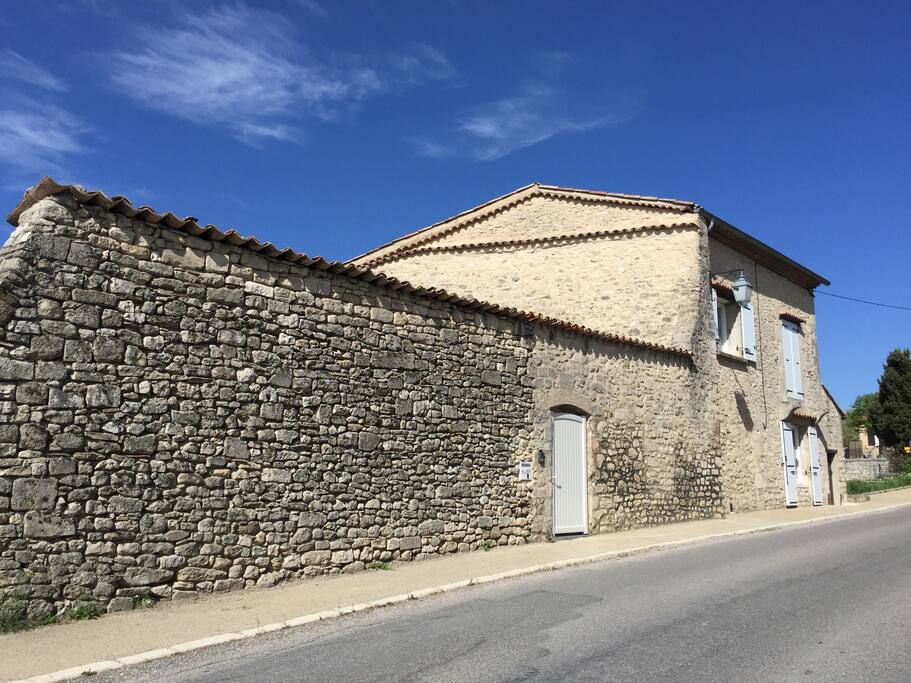 un haut mur de pierre qui protège terrasse et jardin des regards