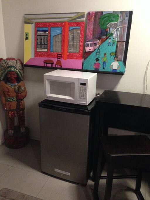 Microwave, Fridge, Dining Table w/ 2 tall chairs + lots of artwork.