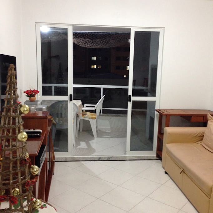 vista geral da sala para saida da sacada da churrasqueira com carrinho de churrasco tela de protecao em todas as janelas