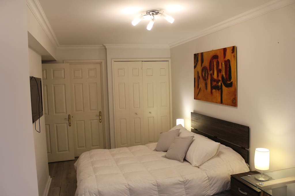 Dormitorio principal con cama matrimonial equipada con televisor HD, escritorio, lámparas, silla, cojines, etc.