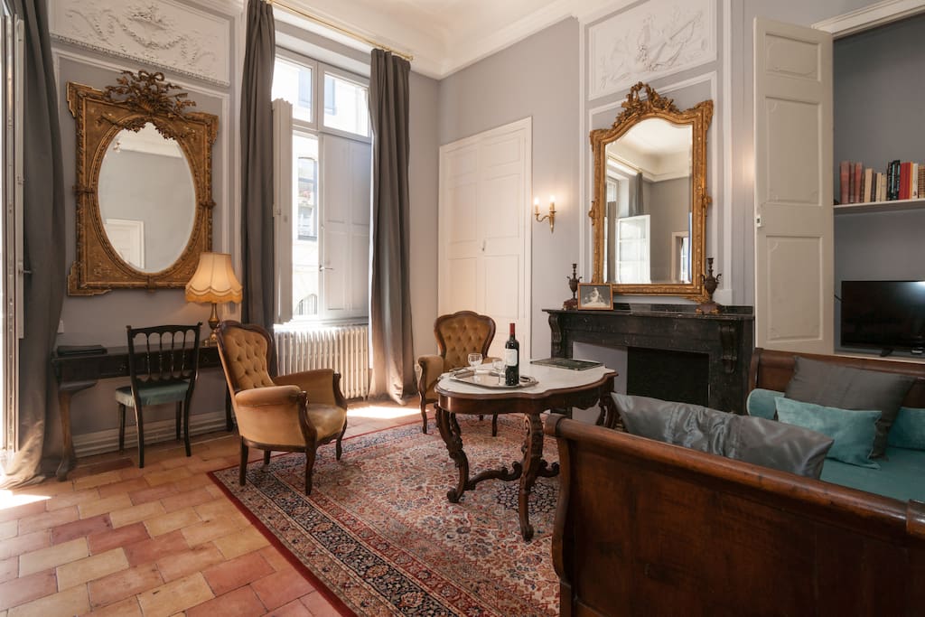 Luxurious living room in French apartment with grey walls, gold ornate mirrors, and Versailles palatial style. #french #apartment #Paris #luxury #vacationrental