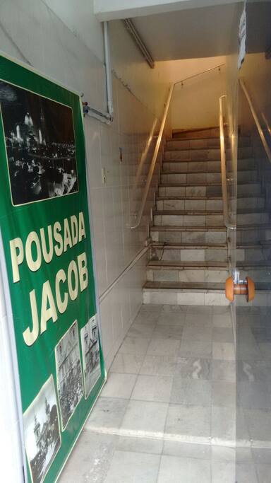 Essa é a entrada principal do prédio , com um cartaz dizendo " pousada Jacob " e três fotos . Uma do Santuario Nacional , que eu mesmo tirei , sou fotógrafo profissional, as outras três embaixo é da igreja velha das quais tive que refazer .