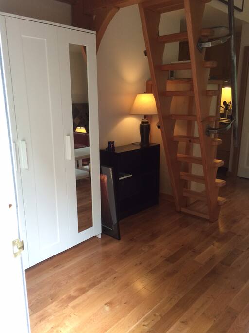 Looking in to the left from the entrance with the stairs/ladder to the loft in front and the kitchen beyond.