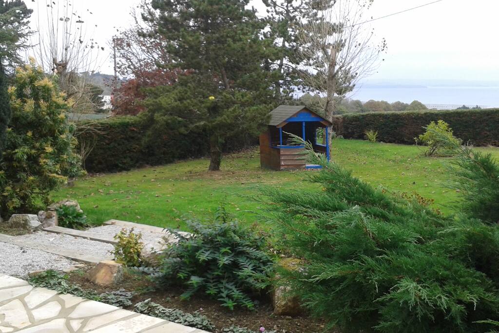 le jardin avec la cabane des enfants et au font la mer