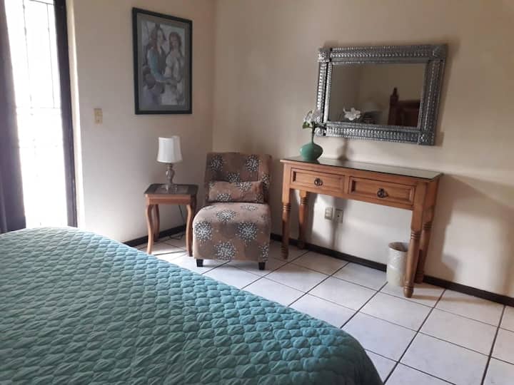 Recámara con ventilador en techo, sillón cómodo.