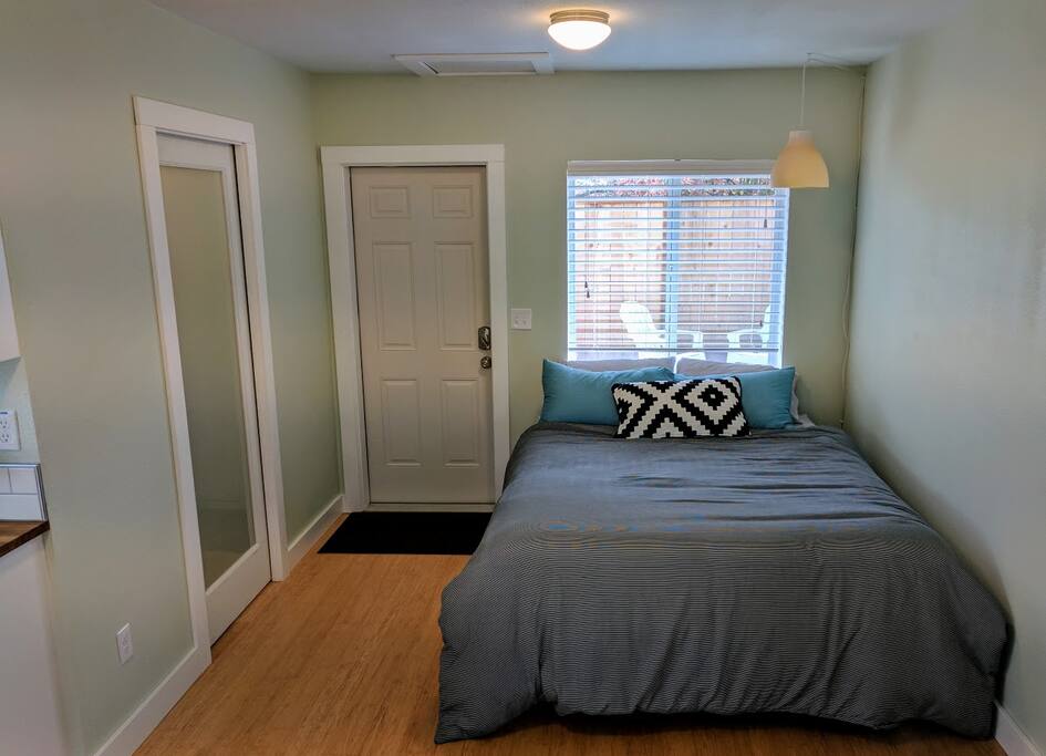 Queen bed with bathroom to the left and patio out the window. Setup as a studio.