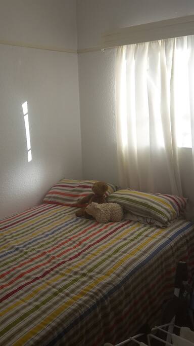 The room contains a double bed, desk and cupboard space
