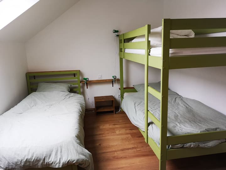 غرفة نوم خضراء في الطابق العلوي بثلاثة أسرّة 