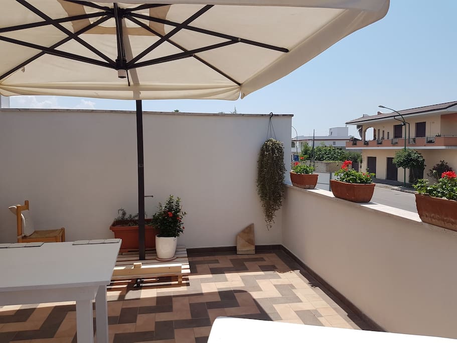 veranda attrezzata con tavolo, sedie e ombrellone