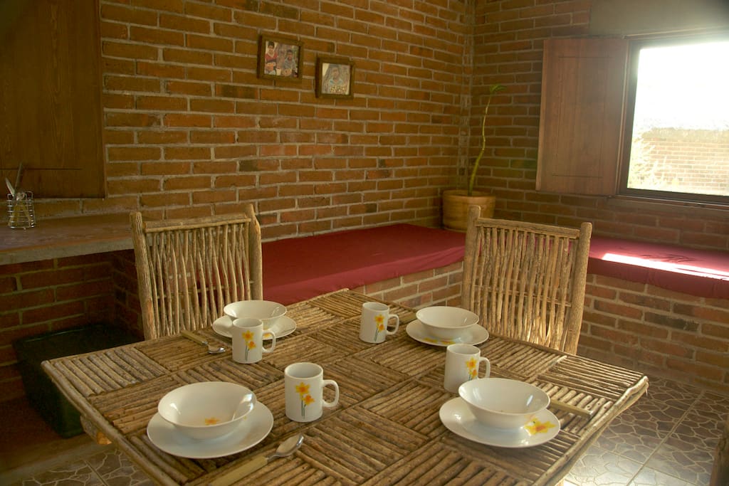 A comfortable dining table with kitchenware for four and the 2 futons behind for the 3rd and 4th guests.