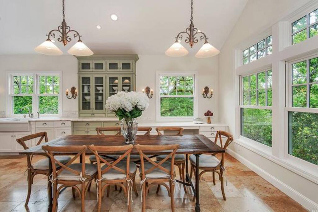Custom built chef's eat-in kitchen, Wolf appliances, double sink-dishwasher configuration, expansive Carrara marble island, beverage fridge, and French doors leading to outdoor dining and spa area.