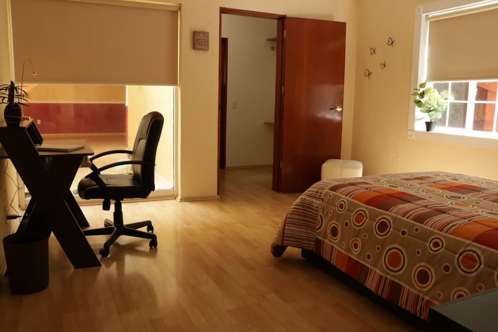 Recámara con cama matrimonial, buró y escritorio.