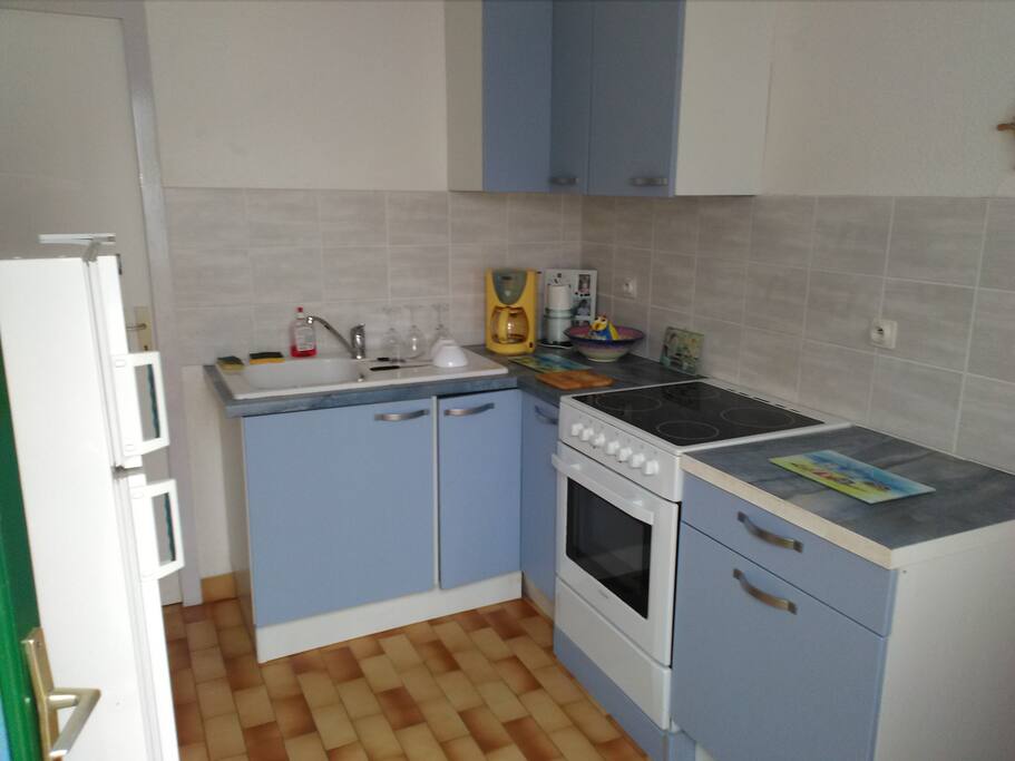 Vue panoramique de la cuisine. Un lave vaisselle se trouve dans le cellier attenant.