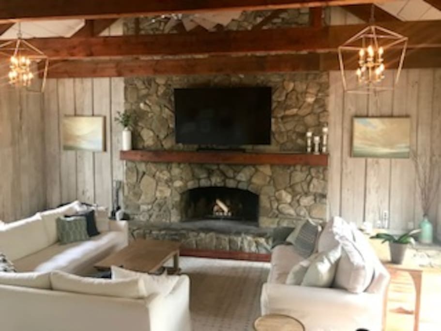 Family room with open beams, a huge stone fireplace, TV, and pull out couch for additional guests
