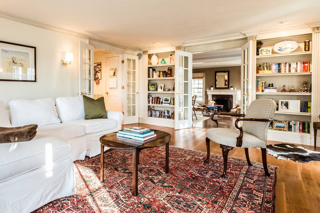 Living room with fireplace and French doors connecting to kitchen, dining/family room, and terrace