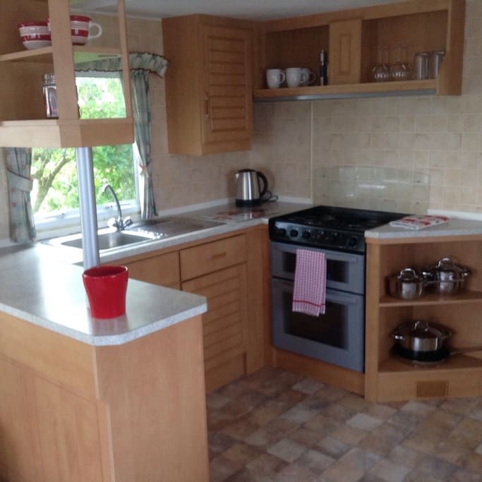 Kitchen with gas oven and hob, microwave, fridge, kettle and toaster. Pans, cutlery, crockery and glassware.