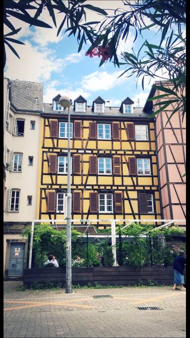 Façade à colombages qui surplombe une terrasse ombragée.