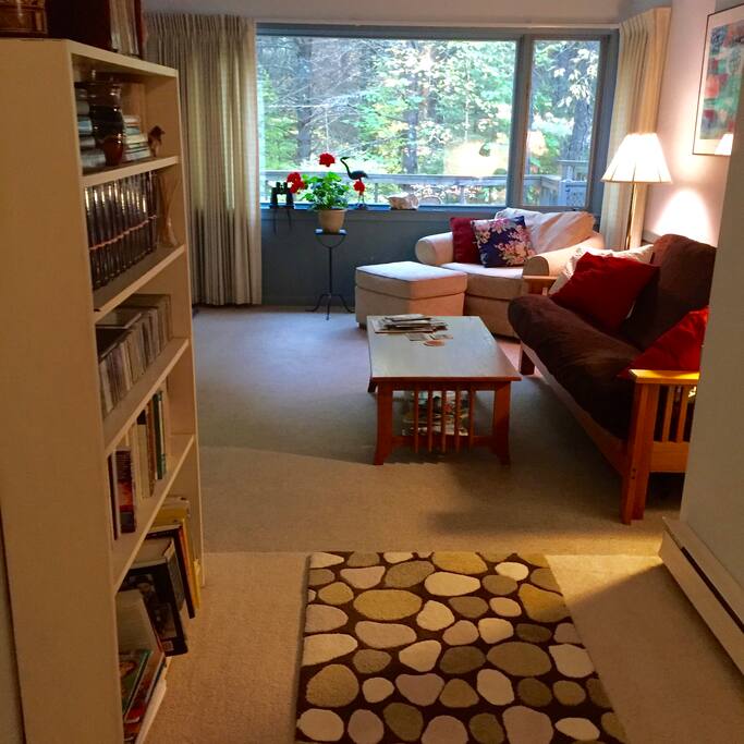 View of the living area from the front door. Windows look out toward the woods and private deck..