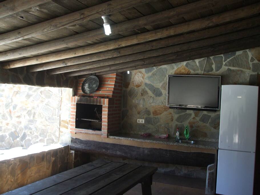 Zona exterior de barbacoa con tv, mesa y nevera