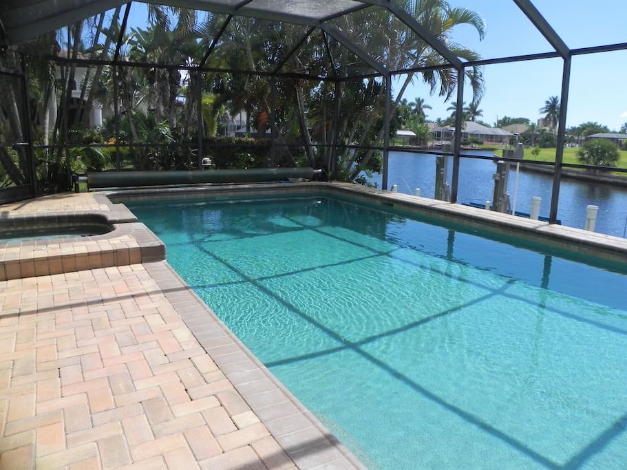 Large solar-heated pool and spa with screened lanai and view of intersecting canals